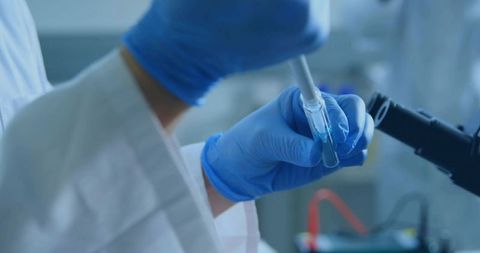 Scientist Pipetting Blue Solution in Laboratory Setting