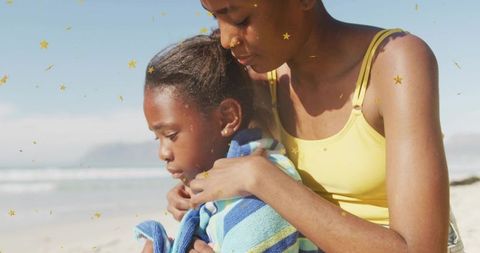 Comforting beach moment wrapping towel around child, sunny shoreline nurturing bond