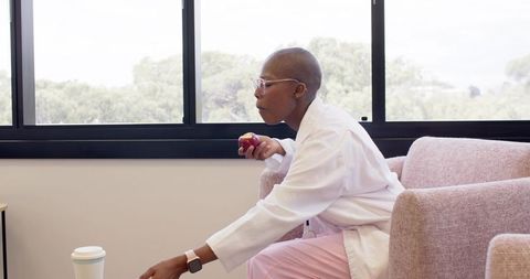 Healthcare professional taking break in lounge holding apple reaching for coffee cup
