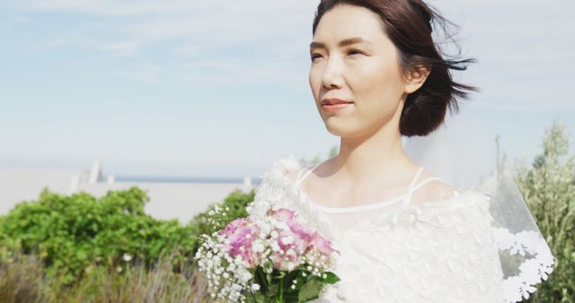 Image of happy asian bride walking holding bouquet and smiling at outdoor wedding. Marriage, love, happiness and inclusivity concept.