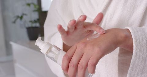 Woman Applying White Lotion in Minimal Bathroom