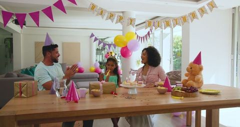Family celebrating child’s birthday with cake and party decor