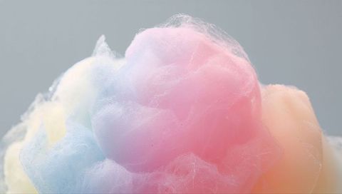 Macro cotton candy tuft filling frame with pastel pink, blue and peach cloudlike fibers