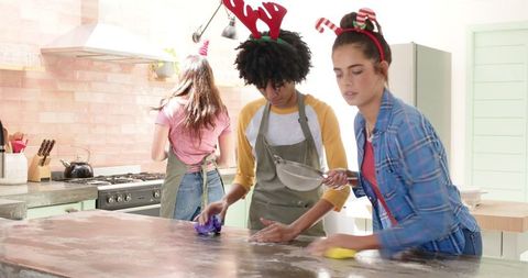 Young friends cleaning kitchen festively together