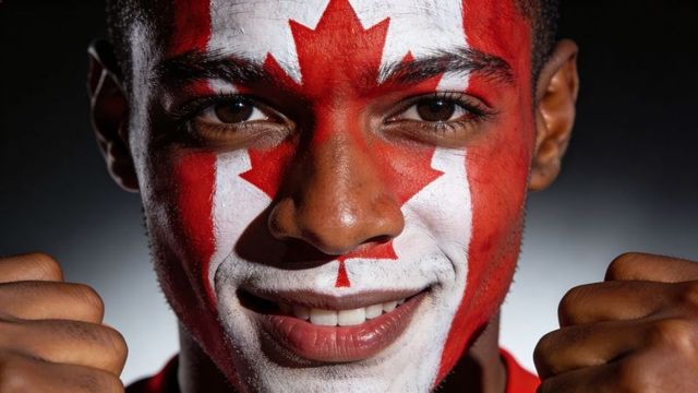 Smiling man wearing canadian flag face paint raising fists close-up patriotic portrait