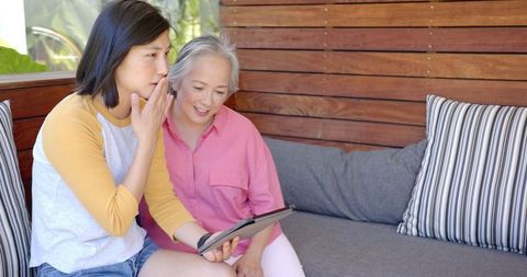 Young Woman Guides Senior in Digital Learning on Tablet Sofa Connection