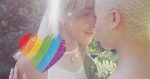 Lgbtq+ female couple embracing with rainbow heart symbol of love