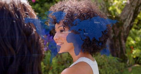 Smiling woman conversing in sunlit garden with blue world map and data overlay