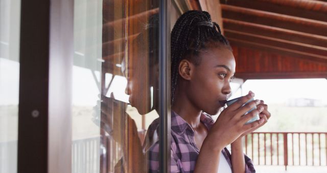 Woman in contemplation sipping coffee on porch while looking out - Download Free Stock Images Pikwizard.com