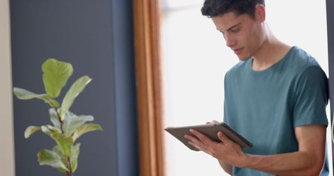 Young Man Engaged with Tablet in Sunlit Living Room