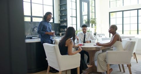 Friends chatting around modern wooden dining table in bright open-plan kitchen