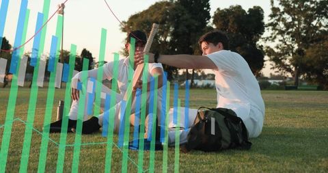Two cricketers sitting on grass adjusting bat and pads while showing sports analytics overlay