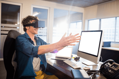 Man with virtual reality glasses working on computer in office