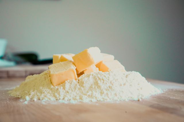 Cubes of butter placed on a mound of flour, ideal for baking recipe tutorials, food blogs or cooking guides. Useful for illustrating pastry making, ingredient preparation, or creating a rustic kitchen atmosphere in culinary websites or cookbooks.