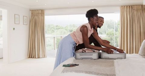Happy couple packing suitcase for tropical getaway
