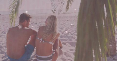 Couple Relaxing Under Palm Trees on Tropical Beach