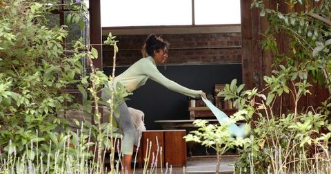 Woman Exercising with Resistance Band on Sunny Garden Patio