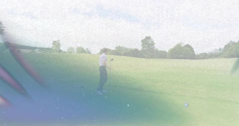 Standing golfer holding driver preparing tee shot on overcast fairway with vintage grain