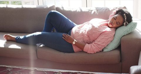 African American Woman Relaxing on Couch, Sunlit Afternoon