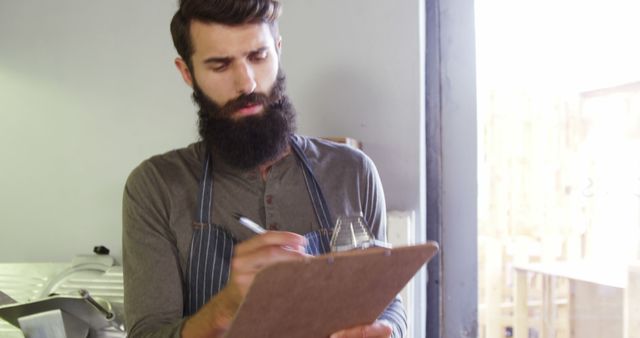 Bearded Barista Taking Inventory in Coffee Shop - Download Free Stock Images Pikwizard.com