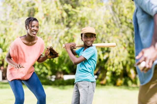 Family enjoying a sunny day playing baseball in a park. Perfect for illustrating family bonding, outdoor activities, and recreational sports. Ideal for use in advertisements, family-oriented campaigns, and articles about healthy lifestyles and family time.