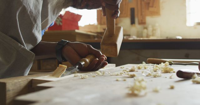 Image of hands of senior african american male carpenter using chisel in carpentry workshop. craft and running small, independent business.