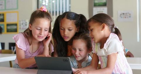 Diverse Girls Collaborating Over Tablet in Elementary Classroom Learning Together