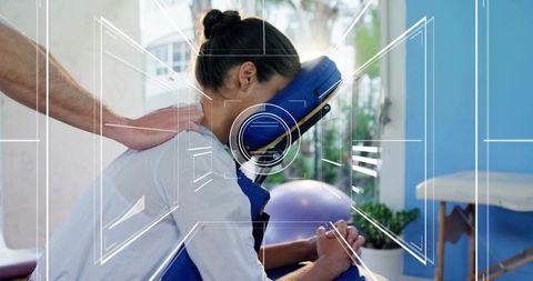 Practitioner giving seated chair massage to woman receiving shoulder therapy in tranquil spa