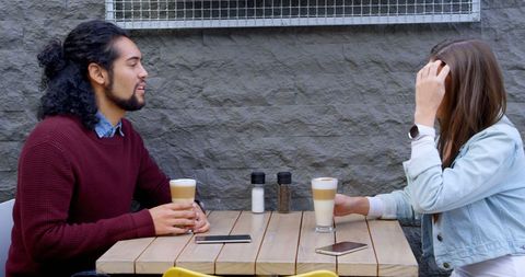 Young people socializing at outdoor café table with coffee