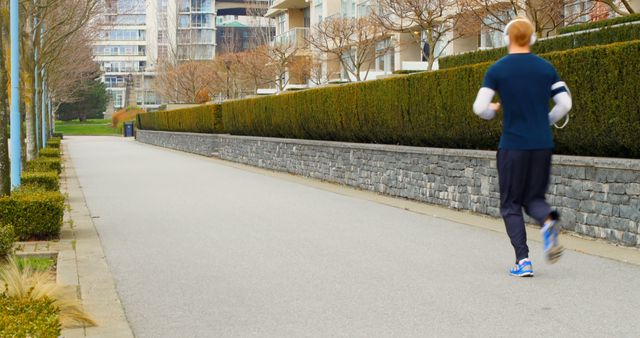 Man jogging along urban path in residential neighborhood - Download Free Stock Images Pikwizard.com