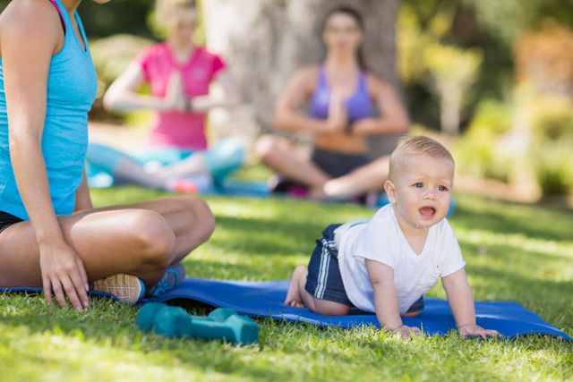 Woman exercising and her baby crawling in park