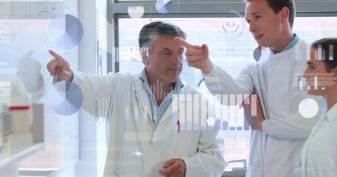 Senior researcher explaining data on glass board with team pointing at digital charts