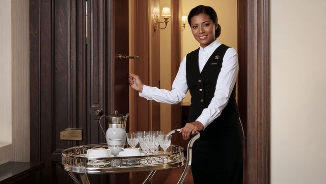 Hotel attendant presenting silver trolley while opening suite door with porcelain tea