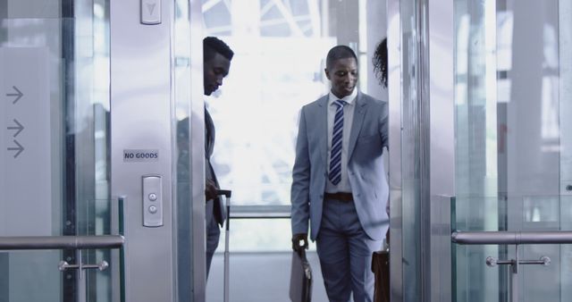 Professionals in business attire entering an elevator in a sleek, modern office building. Useful for depicting a corporate environment, business travel, teamwork scenarios, and urban professional lifestyle for websites, business presentations or marketing materials.