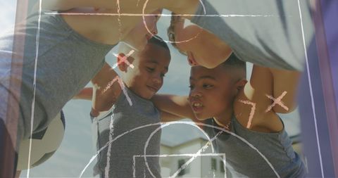 Diverse Schoolboys in Football Huddle with Game Plan