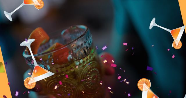Picture captures a close-up of a hand holding a decorative glass filled with a refreshing cocktail and orange slices, surrounded by vibrant confetti, suggesting an ongoing celebration. Ideal for use in advertisements for bars, nightclubs, parties, cocktail recipes, or event invitations.