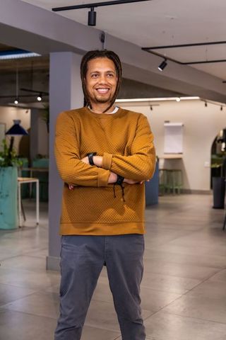 Confident professional standing in modern coworking space with arms crossed and smile