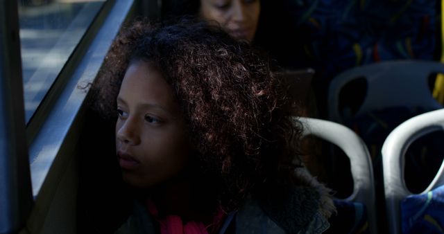 Thoughtful african american girl sitting in city bus looking through window. Childhood, transport, city living and lifestyle, unaltered.