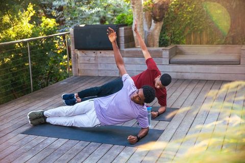 Outdoor side plank workout on deck with two african american men