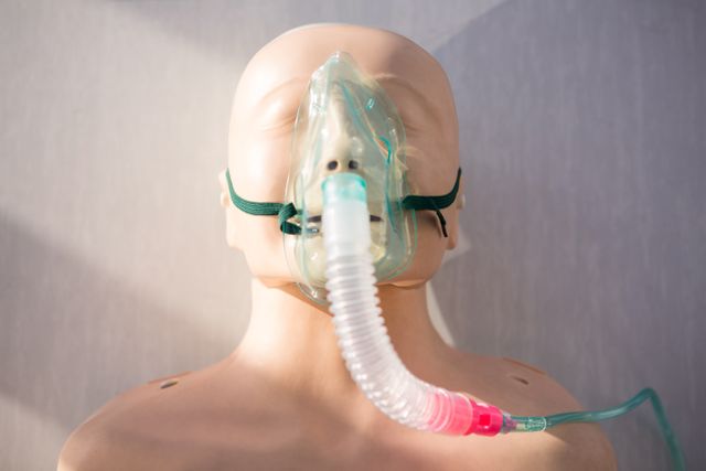 Close-up of a medical dummy wearing an oxygen mask, used for training healthcare professionals in a clinical setting. Ideal for illustrating medical training, emergency preparedness, and patient care education.