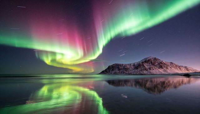 Vibrant northern lights dancing over arctic shore reflecting on tidal flats