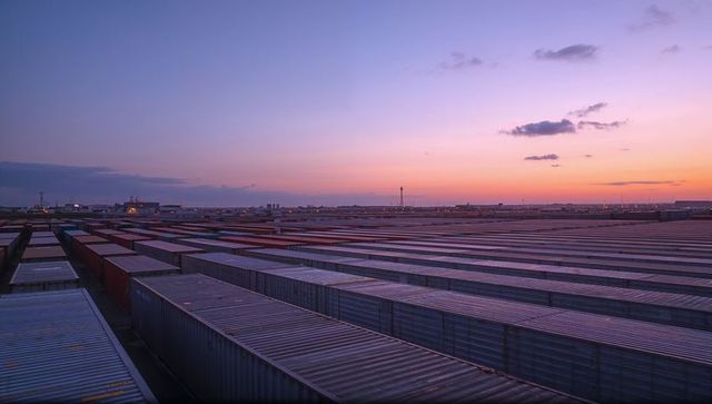 Stretching shipping container rows under twilight sky at industrial port terminal