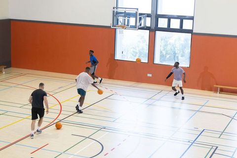 Diverse men playing basketball in bright indoor gym dribbling during pickup game