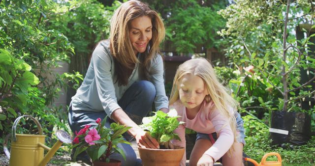 Happy caucasian mother and daughter planting flowers in sunny garden. Family, nature, gardening and hobbies.