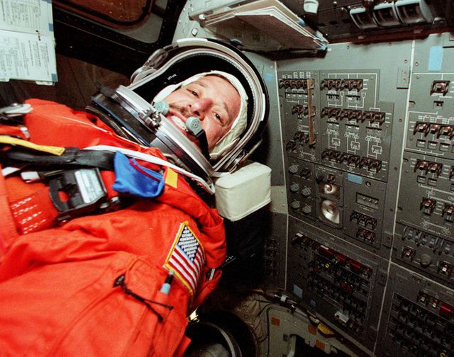 Astronaut Scott J. Horowitz is inside the Space Shuttle Atlantis during a simulated launch countdown. The photo captures Horowitz in his orange space suit, surrounded by various control panels and instruments inside the spacecraft. This image is ideal for articles or presentations related to space missions, astronaut training, and NASA projects. It showcases determination and the technical environment of space exploration, making it valuable for educational content, documentaries, and space-themed publications.