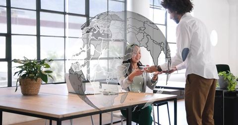 Colleagues passing smartphone across desk with globe overlay for global collaboration