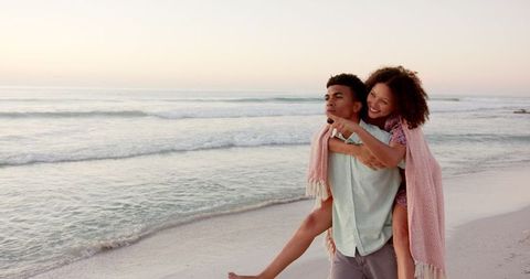 Joyful Couple Embracing Along Tranquil Beach at Sunset