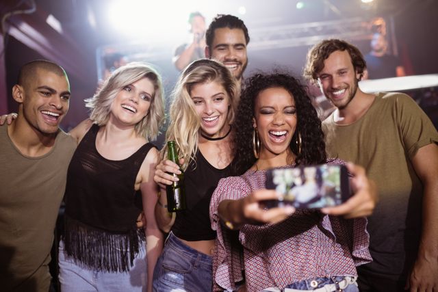 Group of friends enjoying night out at a nightclub, capturing memories with a selfie. Perfect for use in marketing materials for nightlife events, social media campaigns, or advertisements targeting young adults and social gatherings.