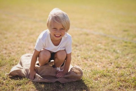 Cheerful Blond Boy Enjoying Outdoor Sack Race Adventure