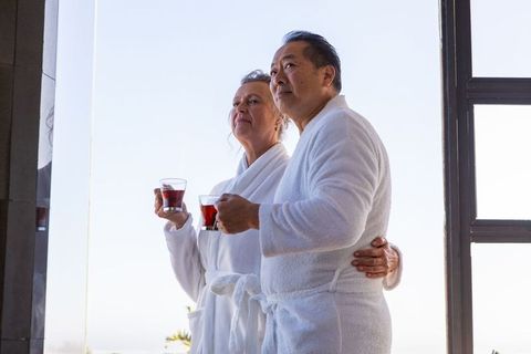 Mature Couple in Bathrobes Sipping Tea on Balcony Relaxing Morning
